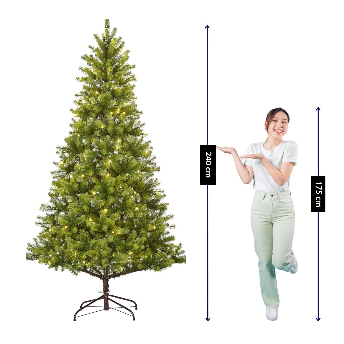 Een staande vrouw poseert naast een verlichte kerstboom van 240 cm.