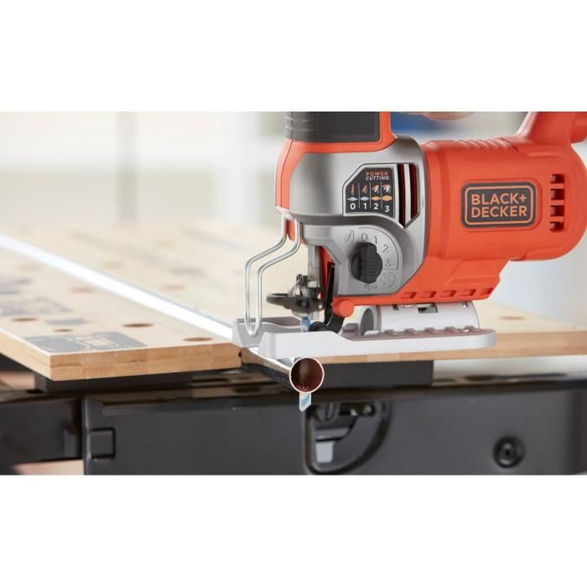 Eine orange-graue Stichsäge von Black+Decker liegt auf einer Werkbank und schneidet ein Metallrohr.