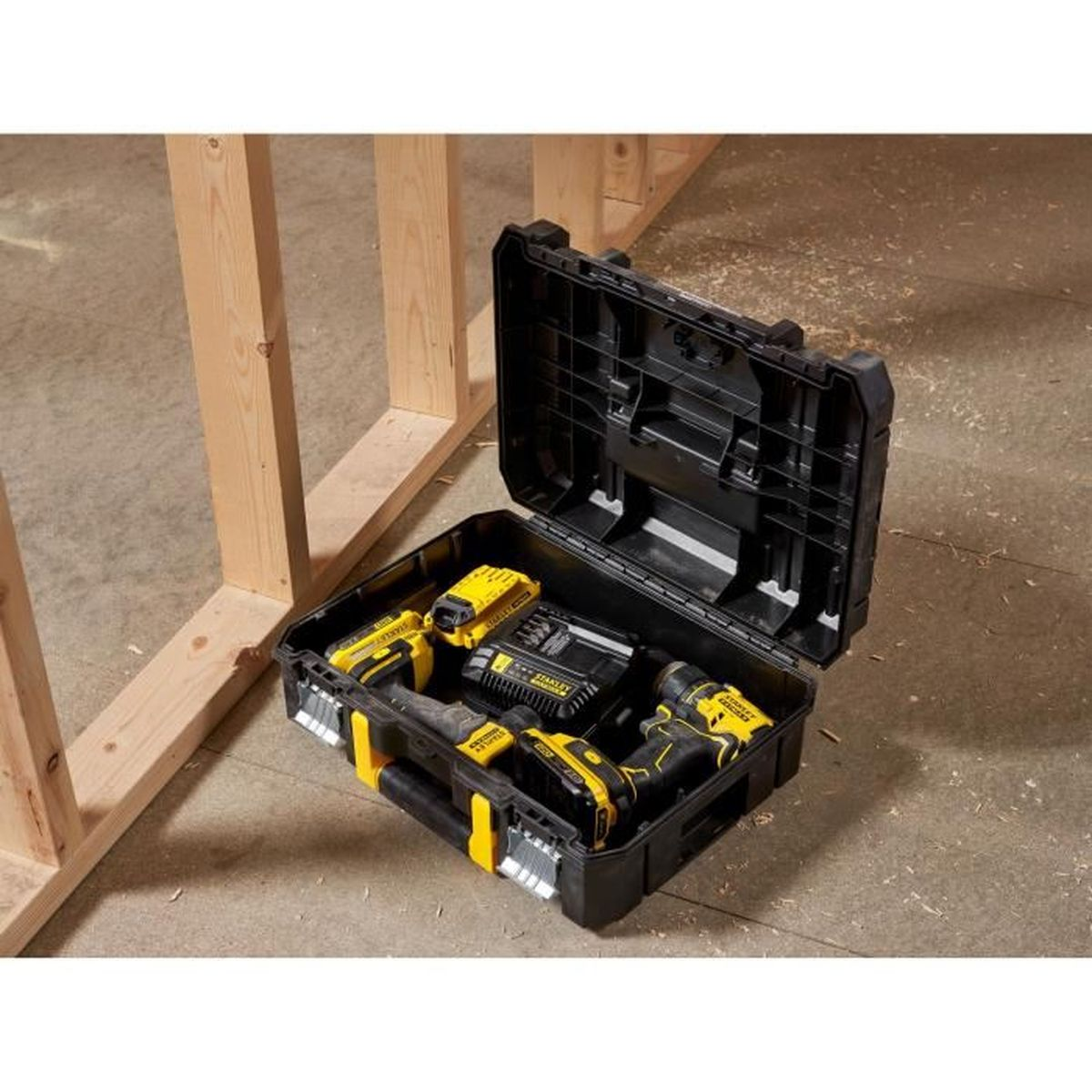 Ein offener, schwarzer Werkzeugkoffer mit gelben Akzenten liegt auf dem Boden neben Holzständern und enthält Elektrowerkzeuge.