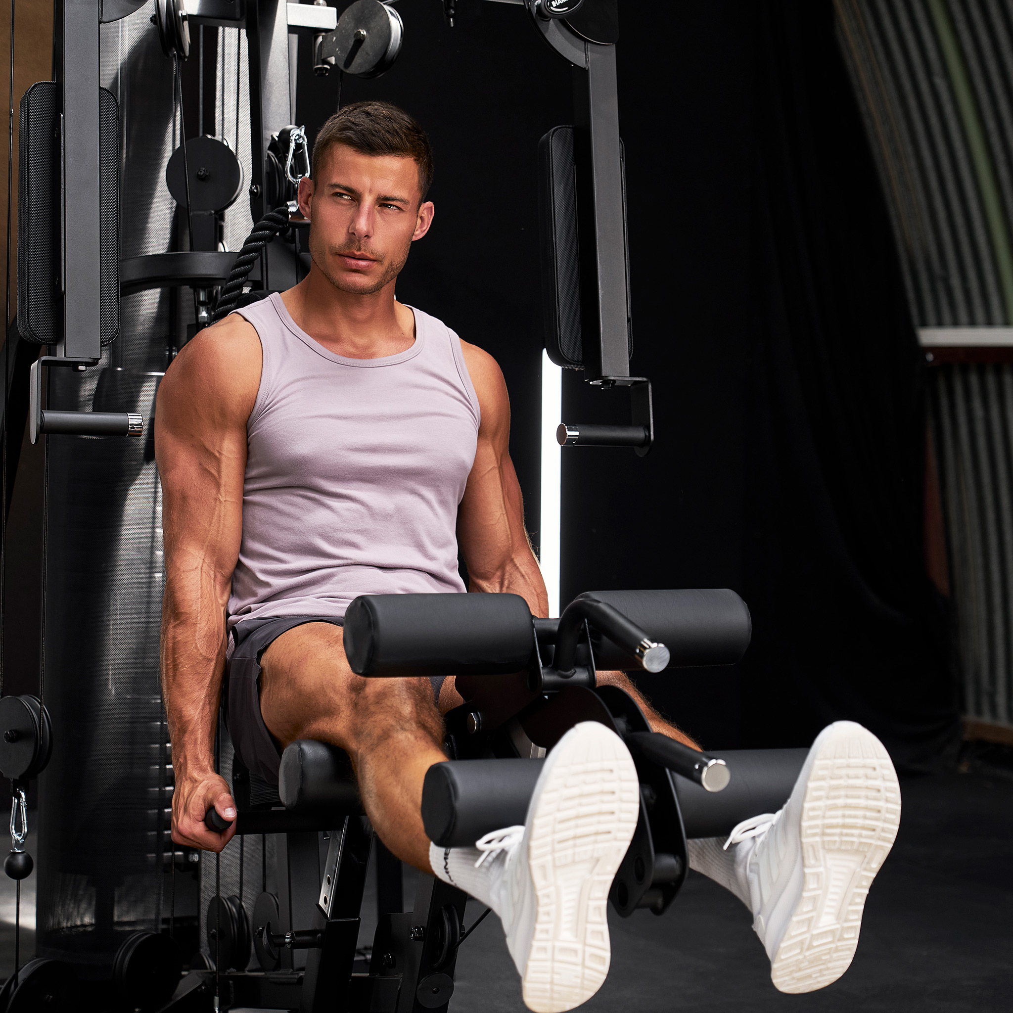 Ein muskulöser Mann sitzt an einer Kraftmaschine und trainiert im Fitnessstudio.