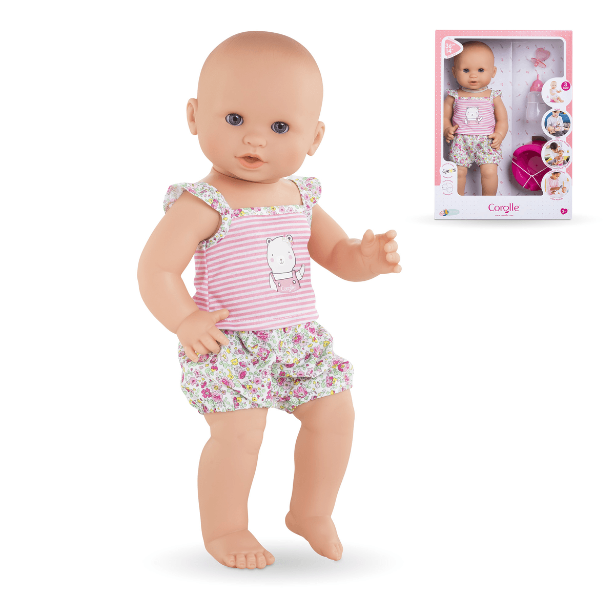 Eine Babypuppe mit gestreiftem Oberteil und Blumenhose steht neben ihrer rosa Verpackung.