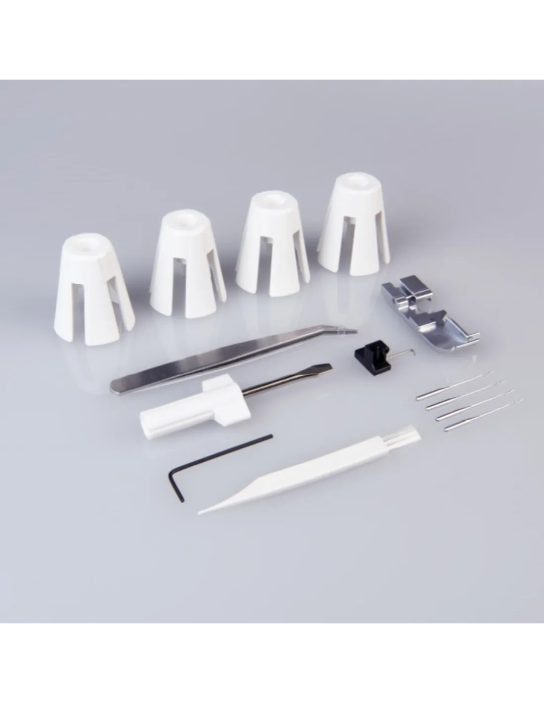 Sewing machine accessories including white spool holders, tweezers, screwdriver, needles, and a cleaning brush.