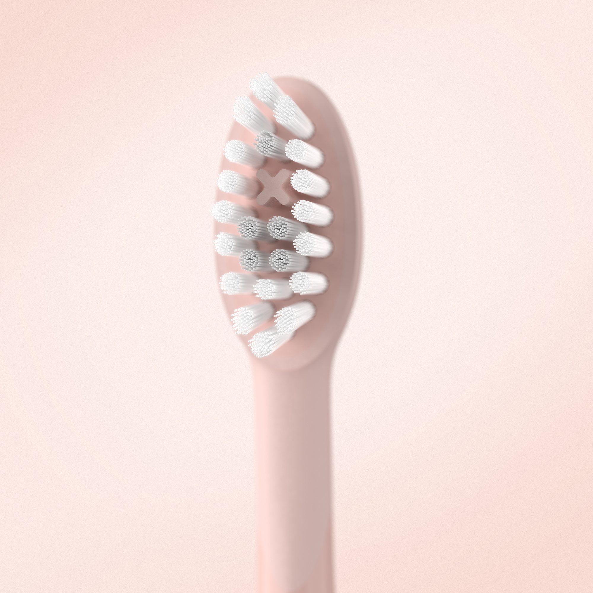 Primo piano di una testina di spazzolino rosa con setole bianche su sfondo rosa tenue.
