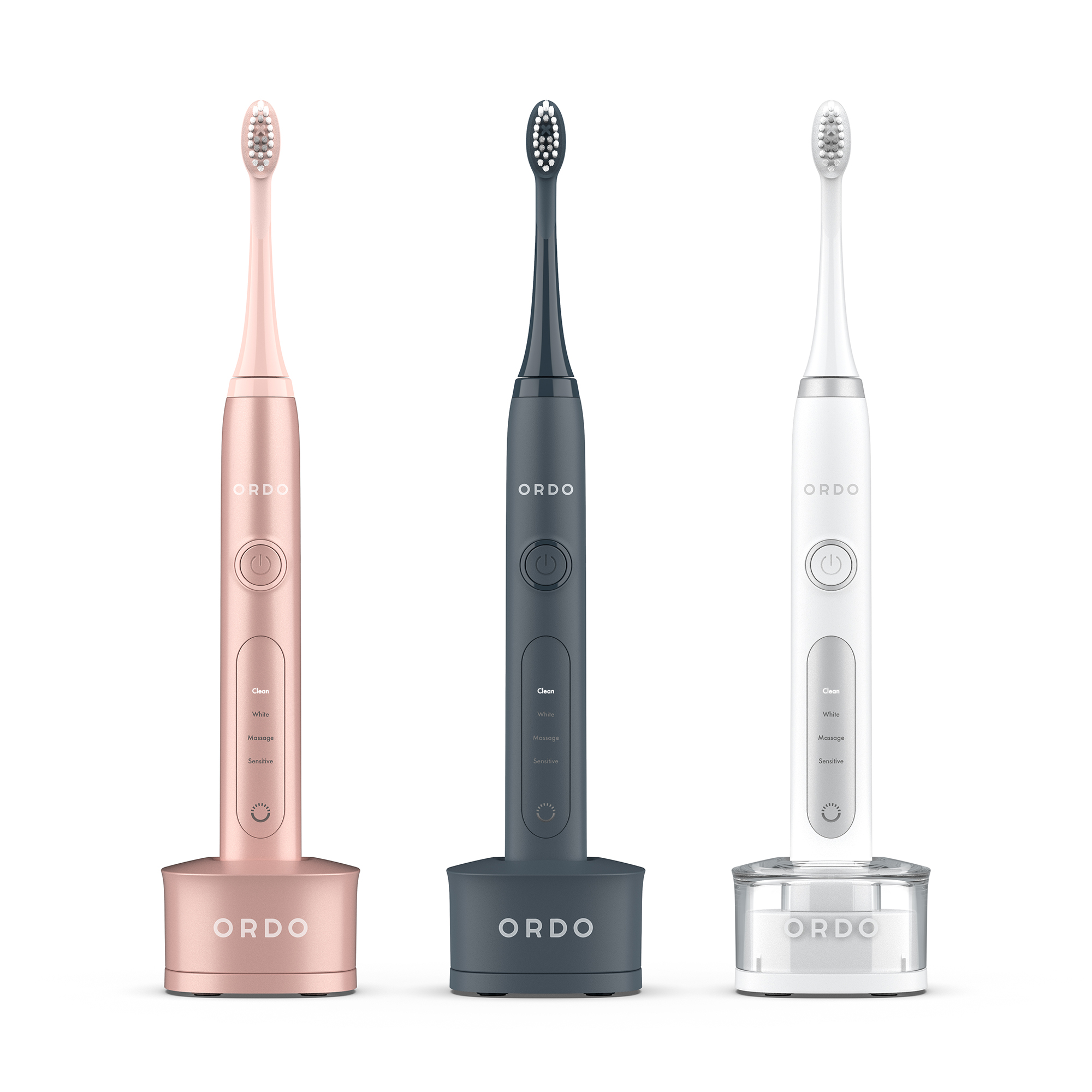 Tre spazzolini elettrici Ordo rosa, blu scuro e bianco su basi di ricarica con sfondo bianco.