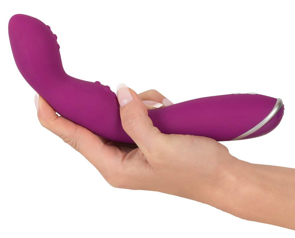 Eine Hand hält ein geschwungenes, violettes Silikon-Sexspielzeug vor weißem Hintergrund.