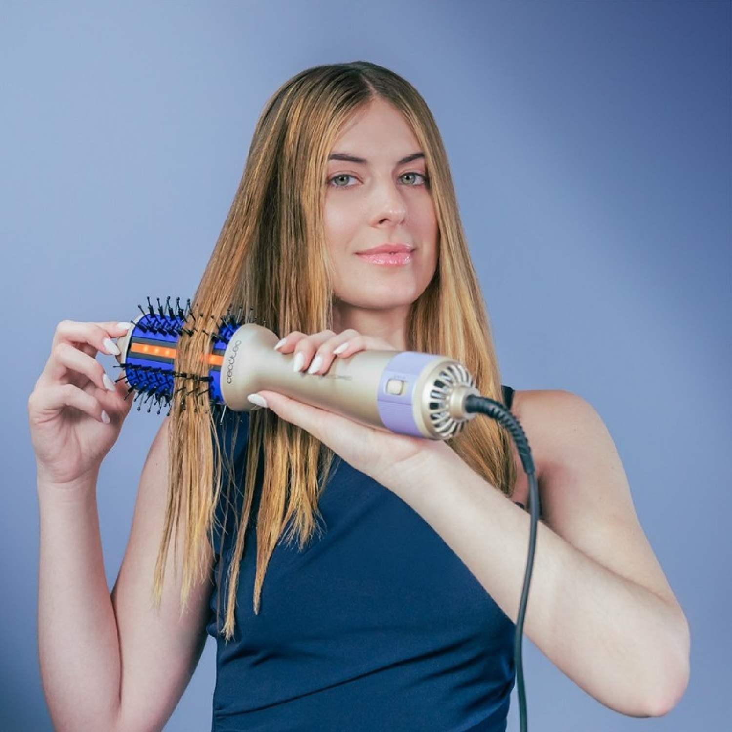 Donna con capelli biondi tiene una spazzola ad aria calda blu e oro.