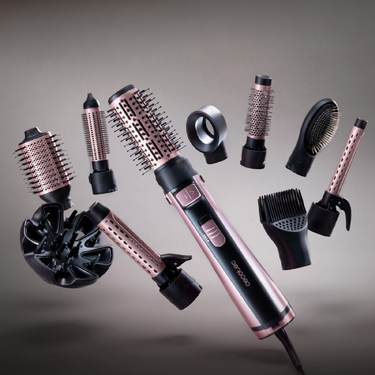 Un multistyler nero e oro rosa con vari accessori fluttuanti su sfondo grigio.