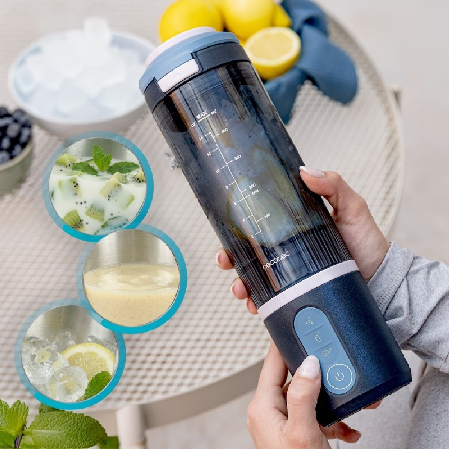Mano regge un frullatore portatile, con limoni, ghiaccio ed esempi di smoothie.
