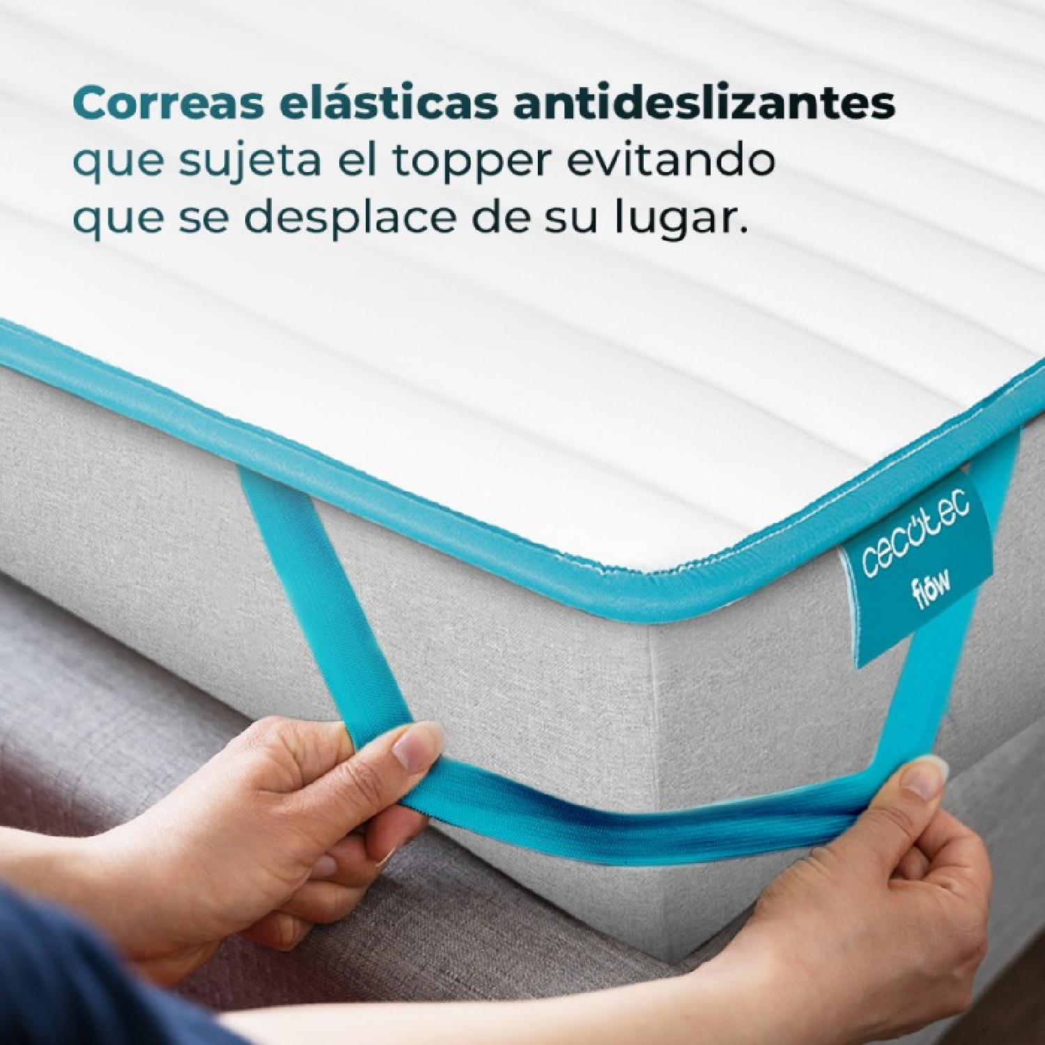 Manos tirando de correas elásticas azules en un sobrecolchón blanco para asegurarlo.