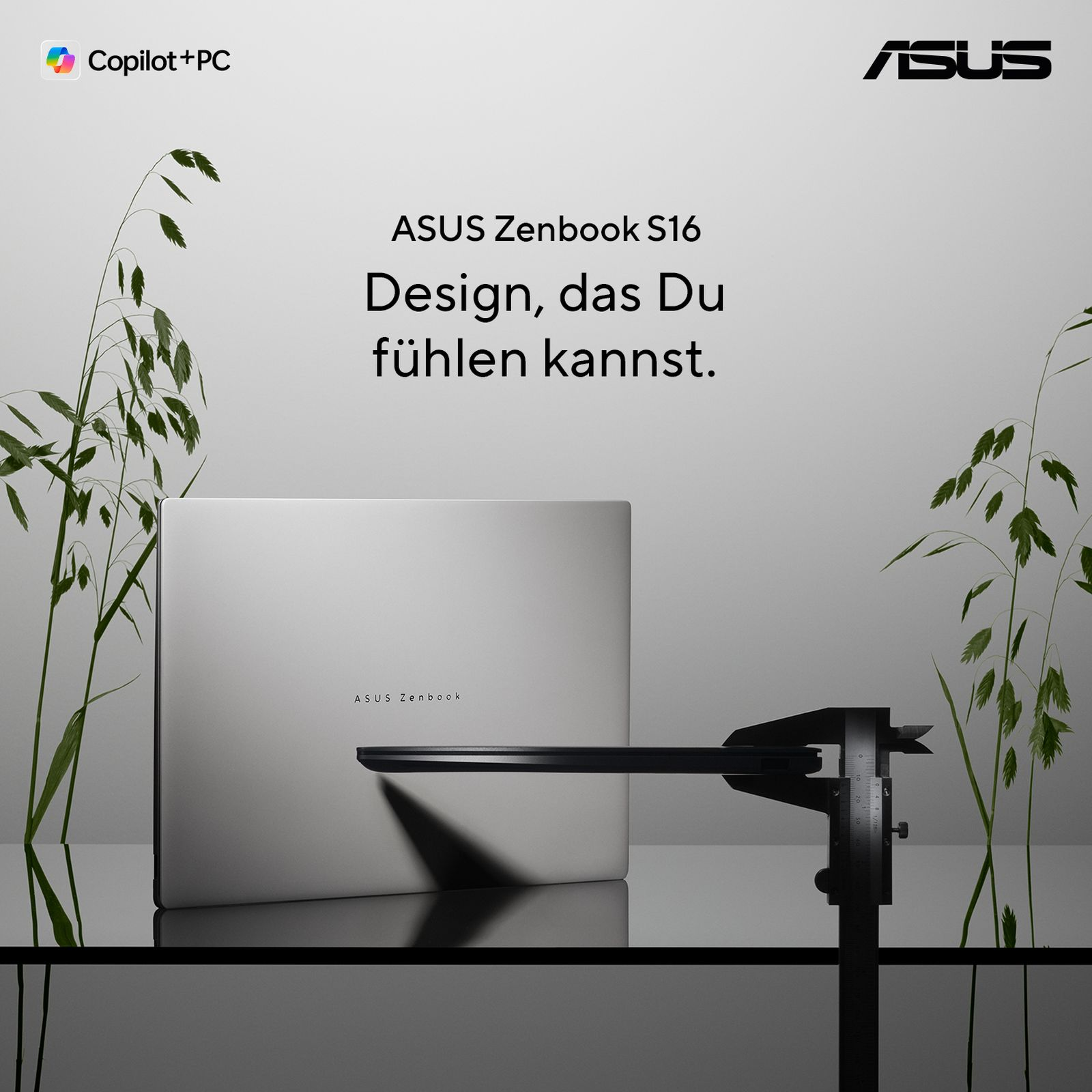 Ein geschlossener ASUS Zenbook S16 Laptop auf einer spiegelnden Fläche, gemessen mit einem schwarzen Messschieber.