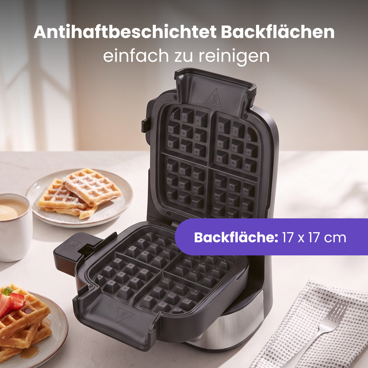 Ein offenes Waffeleisen steht auf einem Tisch mit Tellern voller Waffeln.