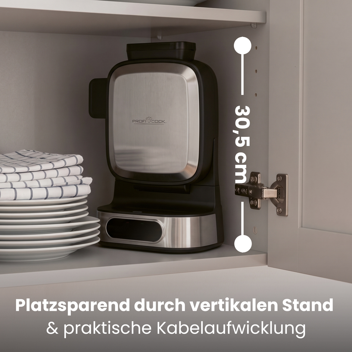 Waffeleisen in einem Küchenschrank neben einem Stapel Teller und gefalteten Tüchern, Höhe 30,5 cm.
