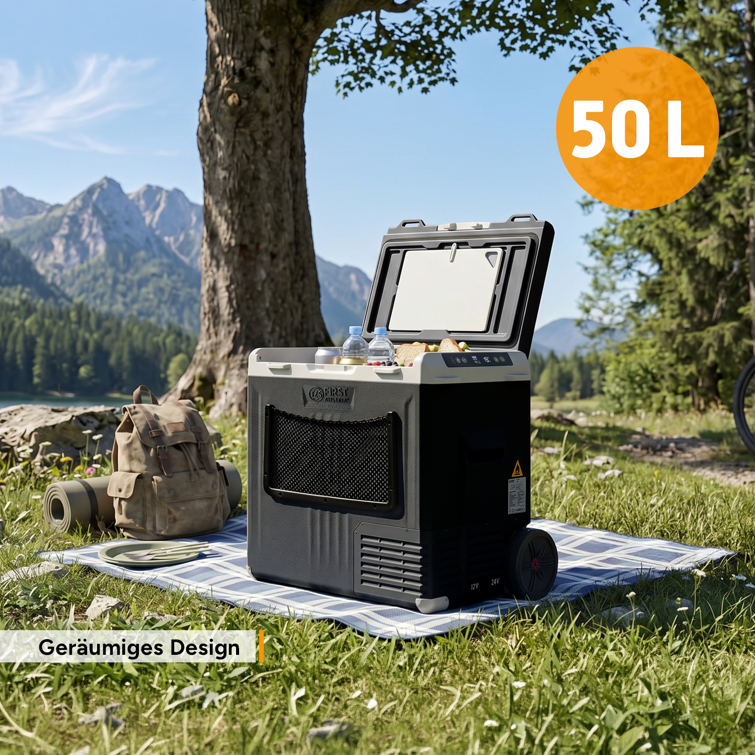 Eine offene Kühlbox auf einer Picknickdecke im Freien, mit Bergen und einem Baum im Hintergrund.