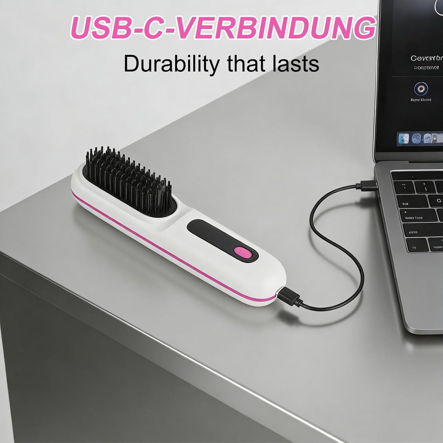 Eine weiß-rosa Haarglättungsbürste mit USB-C-Kabel an einem Laptop auf einem grauen Schreibtisch.