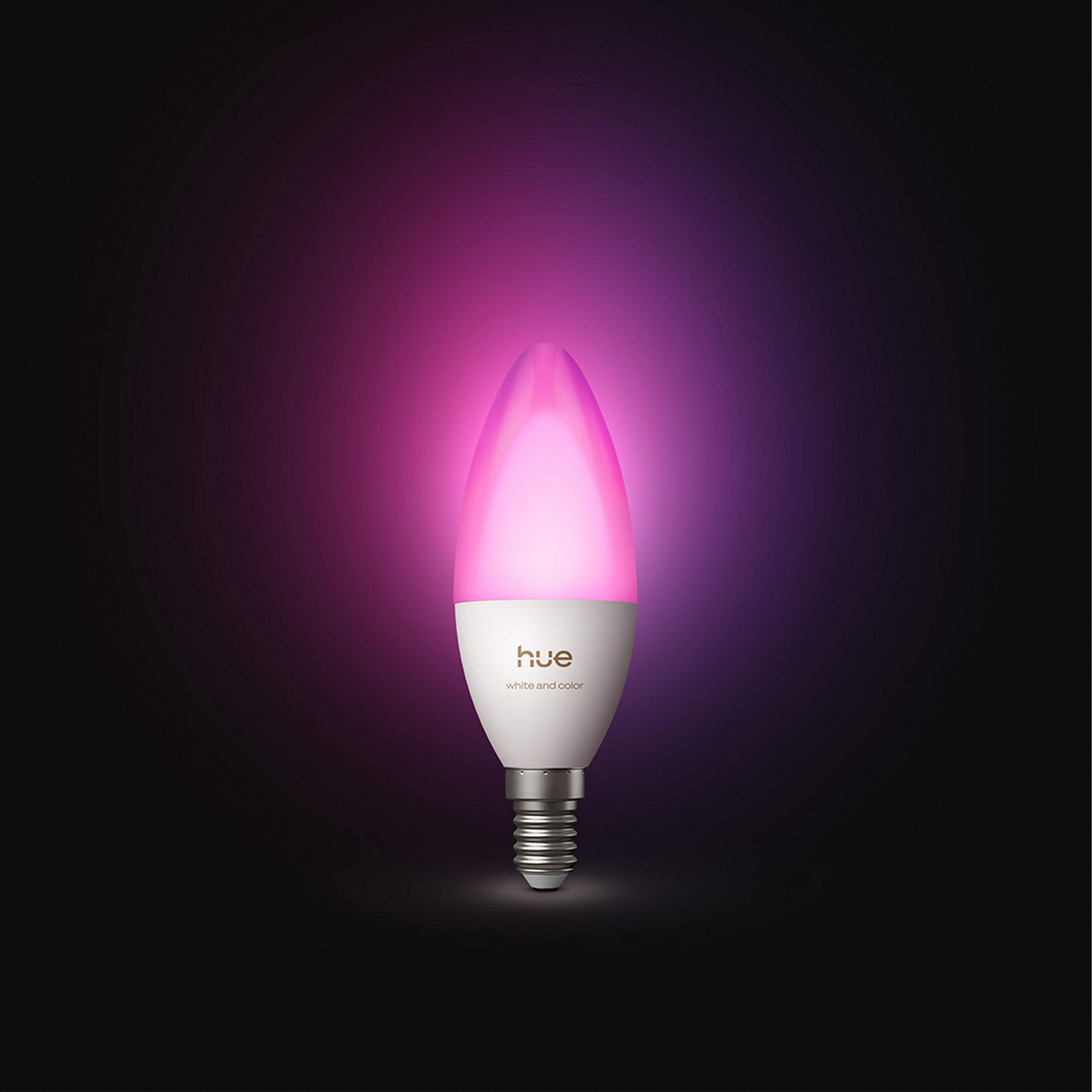 Eine brennende Hue LED-Kerzenlampe leuchtet in leuchtendem Rosa vor einem dunklen Hintergrund.