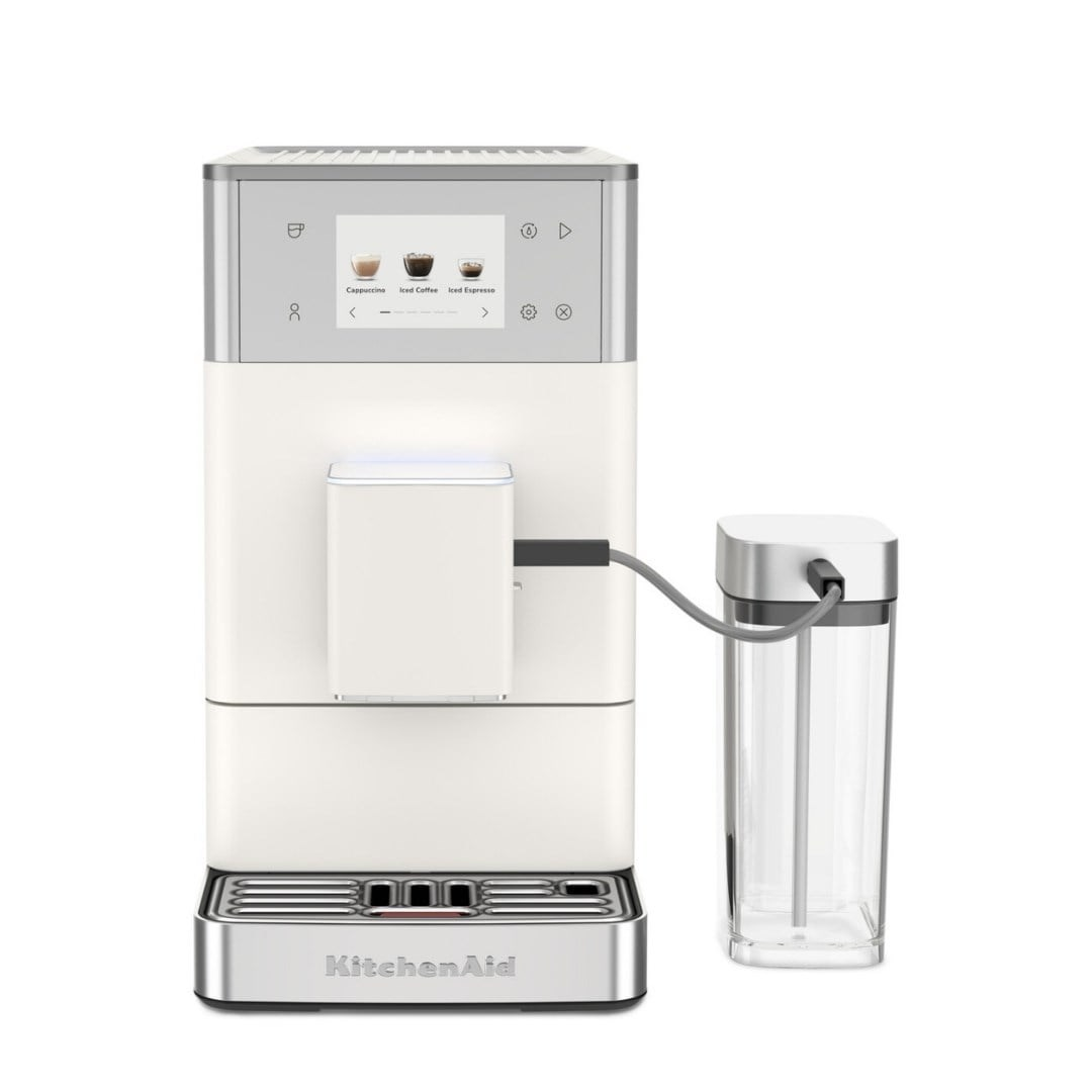 Dokunmatik ekranlı ve şeffaf süt haznesine sahip beyaz KitchenAid tam otomatik kahve makinesi.