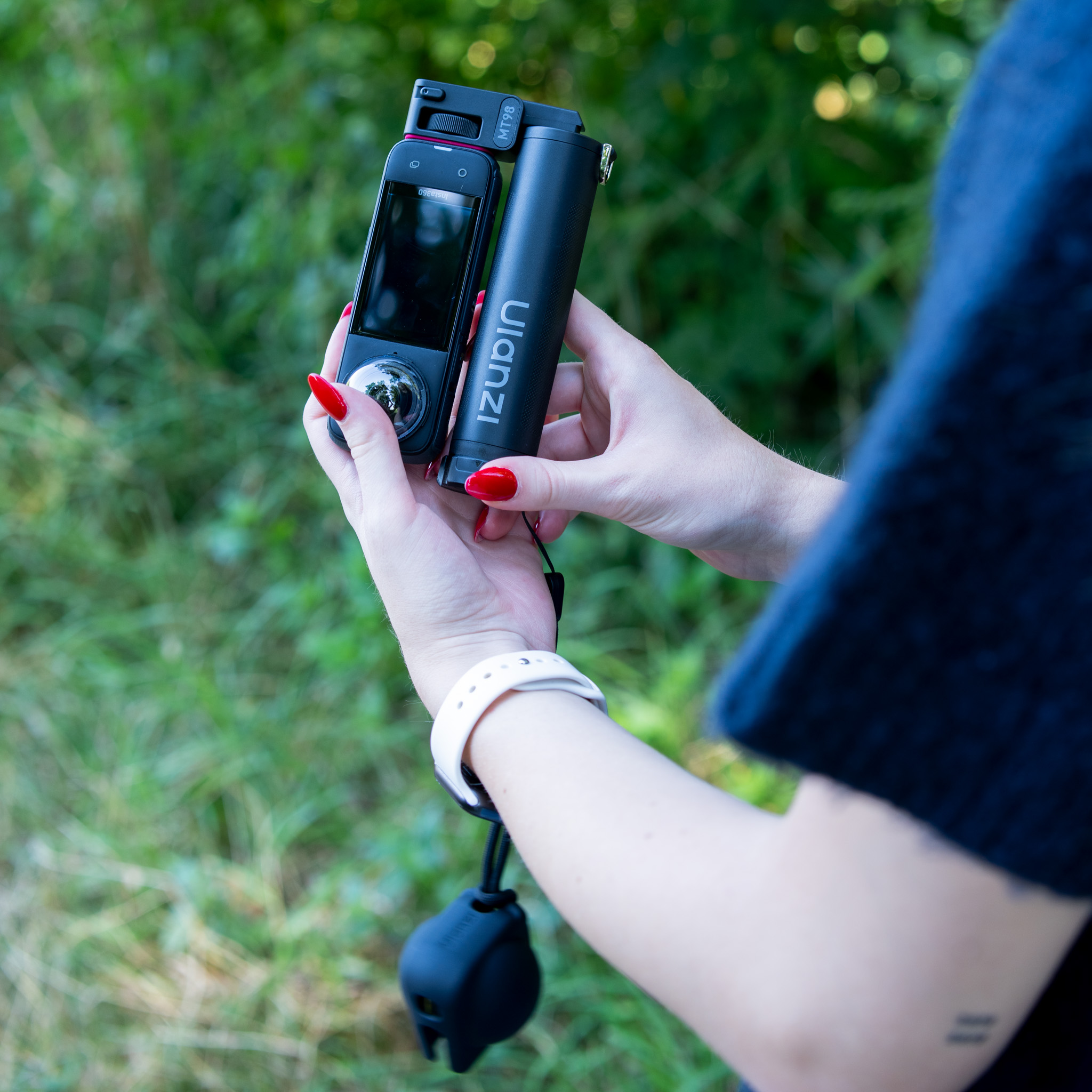 A person holds a Ulanzi 360-degree camera and a matching handle against a green background.