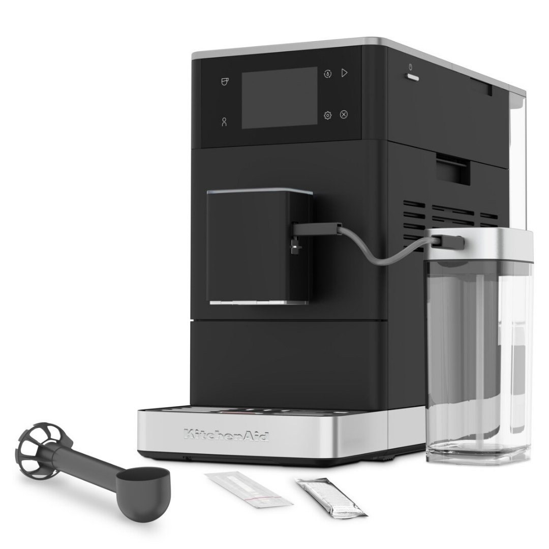 Süt hazmalı, kaşıklı ve temizlik paketli siyah KitchenAid espresso makinesi.