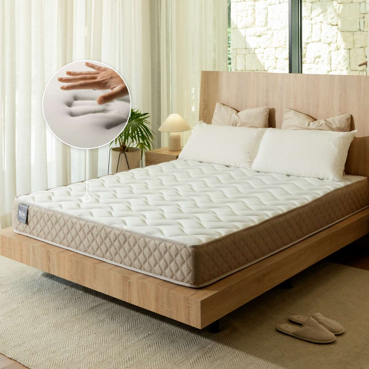 Una cama en un dormitorio luminoso, con una mano presionando una inserción de espuma viscoelástica.