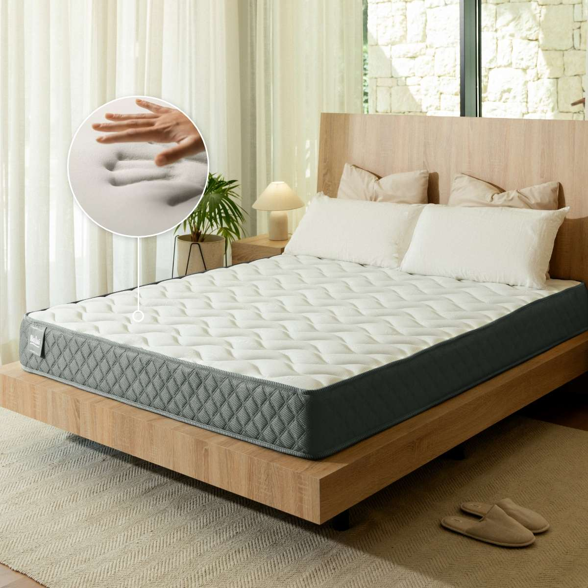 Una cama blanca y gris con cojines y un inserto que muestra la espuma.