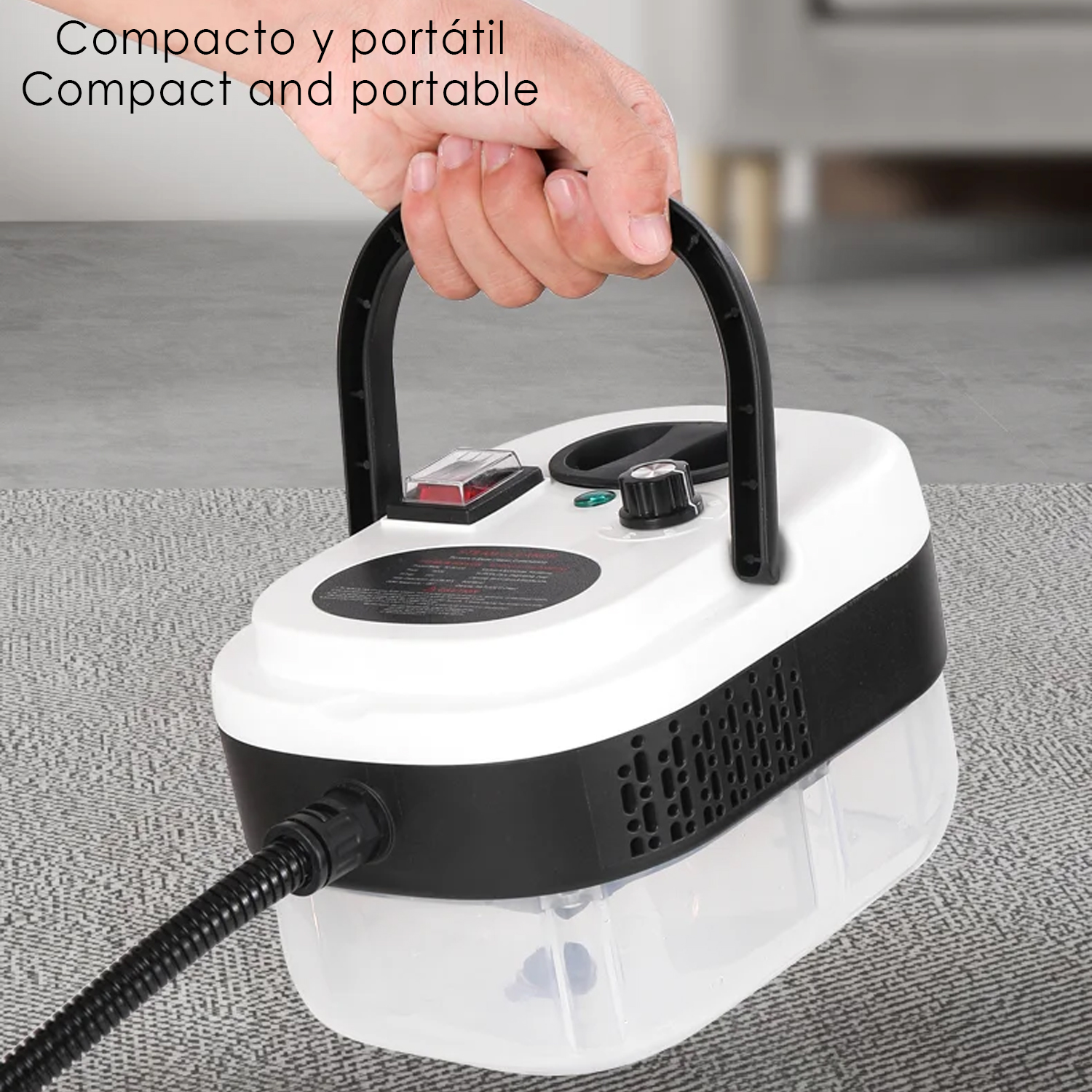 Una mano sostiene un limpiador a vapor portátil blanco y negro por su asa.