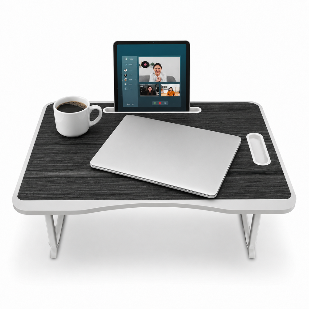 Un escritorio negro para regazo con una laptop cerrada, una tablet con videollamada y una taza blanca.