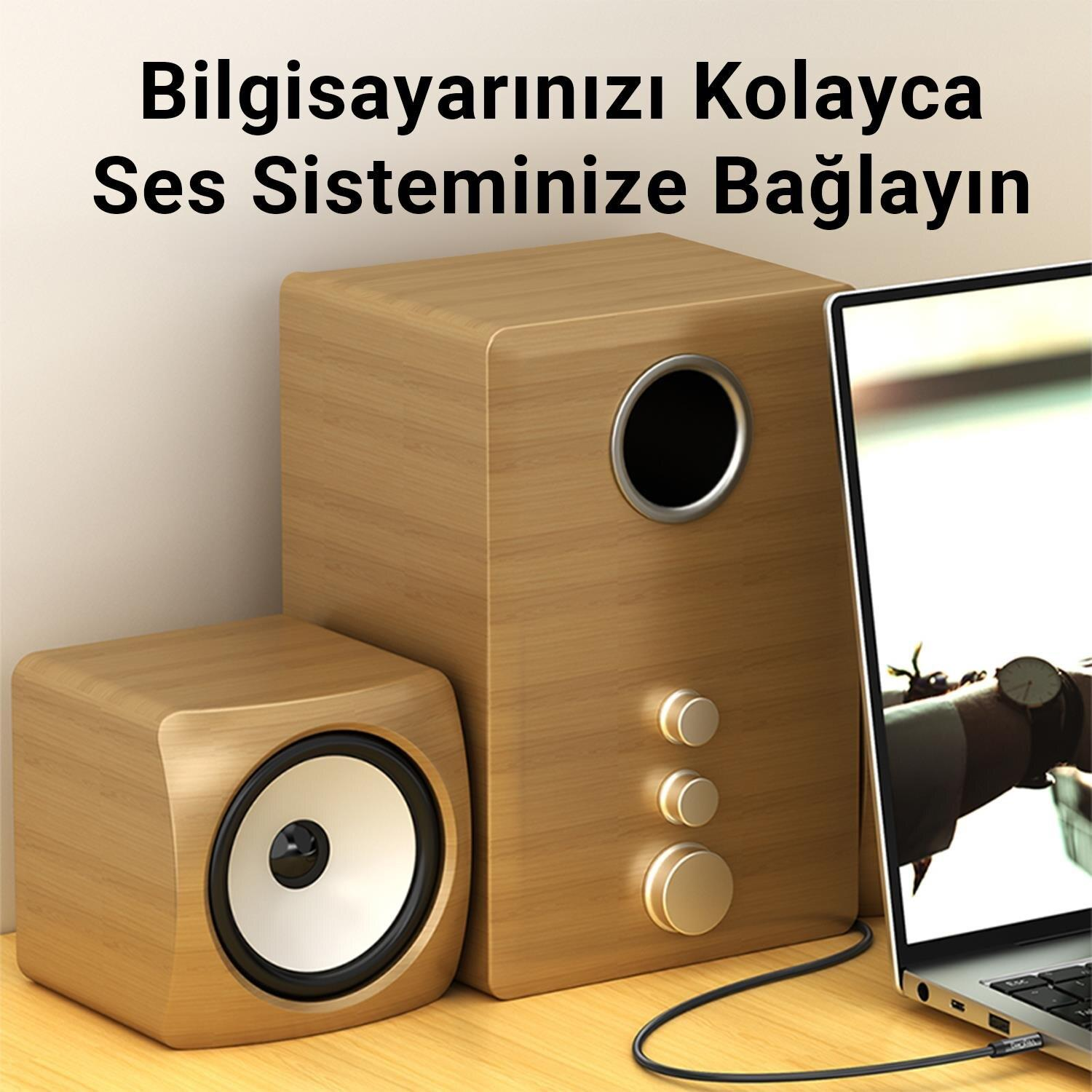 Bir dizüstü bilgisayarın yanında, masada iki ahşap hoparlör duruyor.