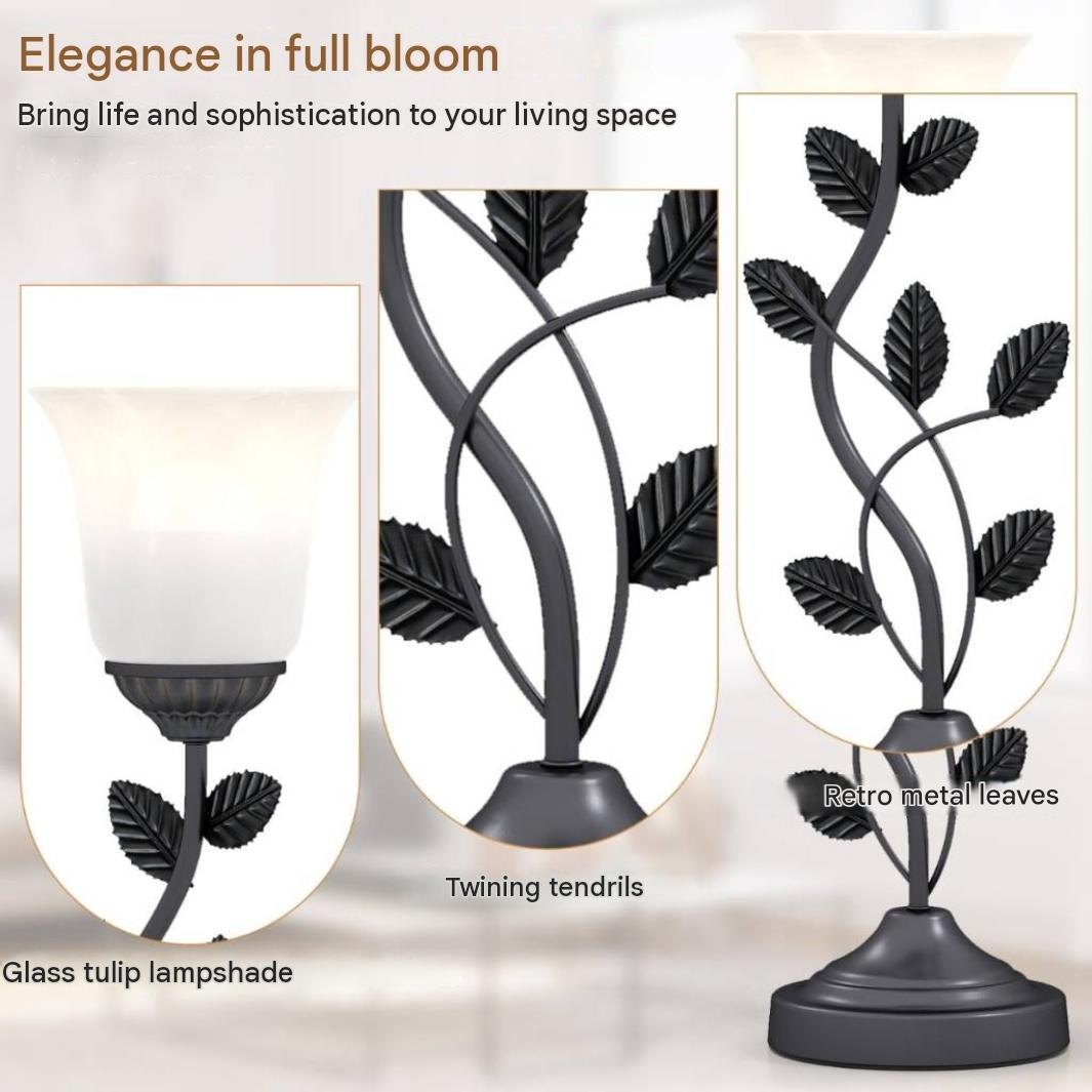 Een staande lamp met metalen bladeren, glazen tulp-lampenkap en ranken.
