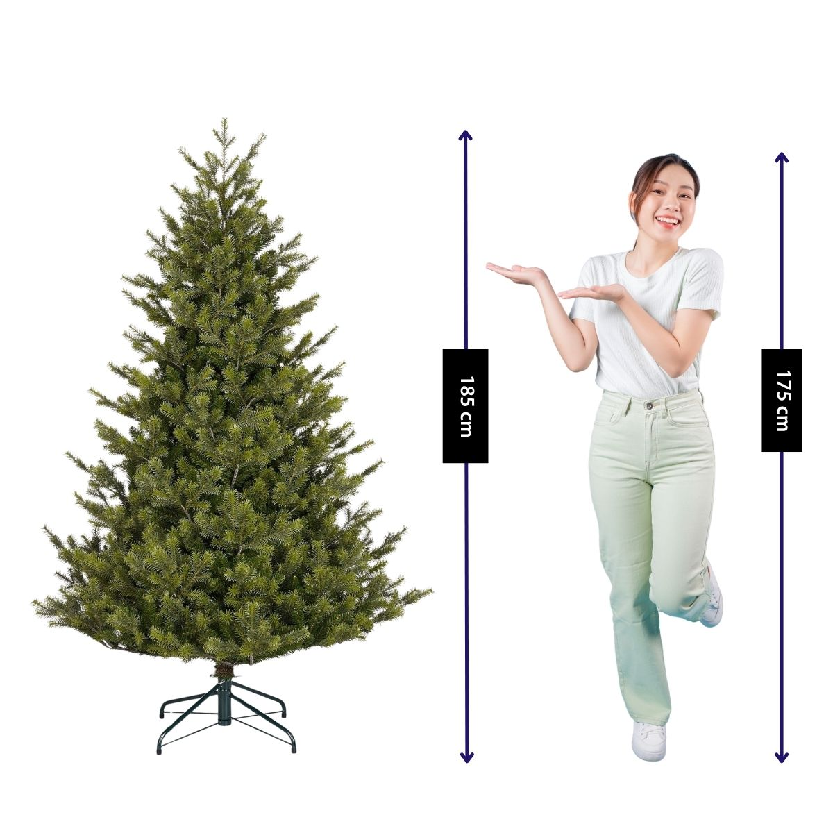 A woman in a white shirt stands next to a 185 cm artificial Christmas tree, gesturing towards it.
