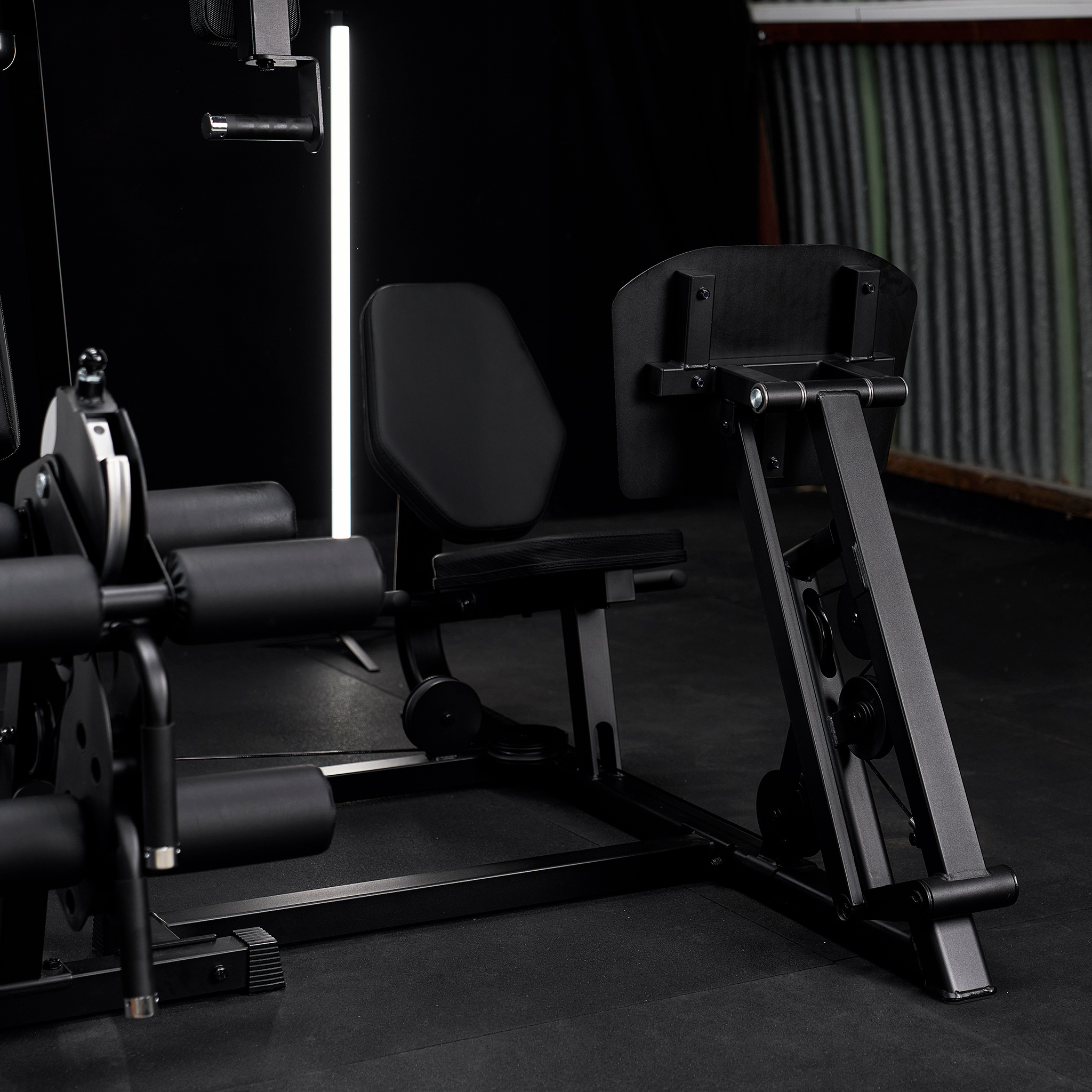 Schwarze Fitnessgeräte in einem modernen Fitnessstudio mit vertikaler Beleuchtung und dunklem Boden.