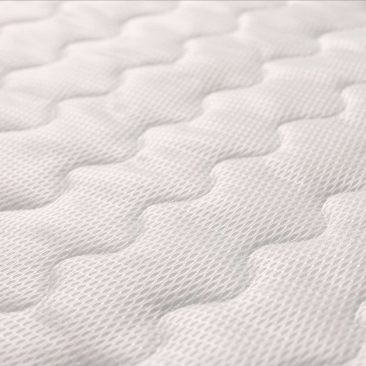 Primer plano de la superficie de un colchón blanco con un patrón de ondas acolchado.