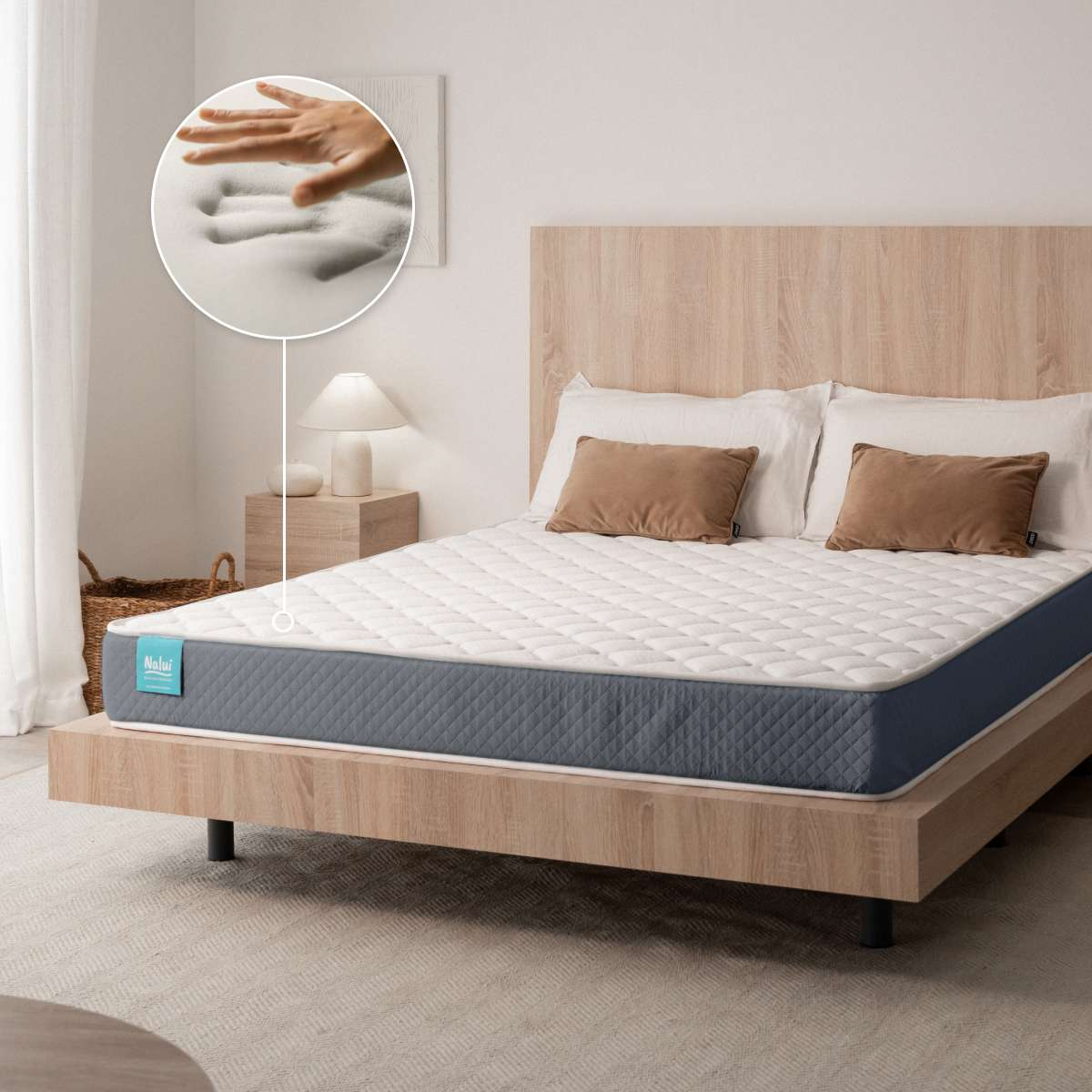 Un colchón sobre una cama de madera con cojines grises y marrones, y un círculo que muestra el efecto memoria.