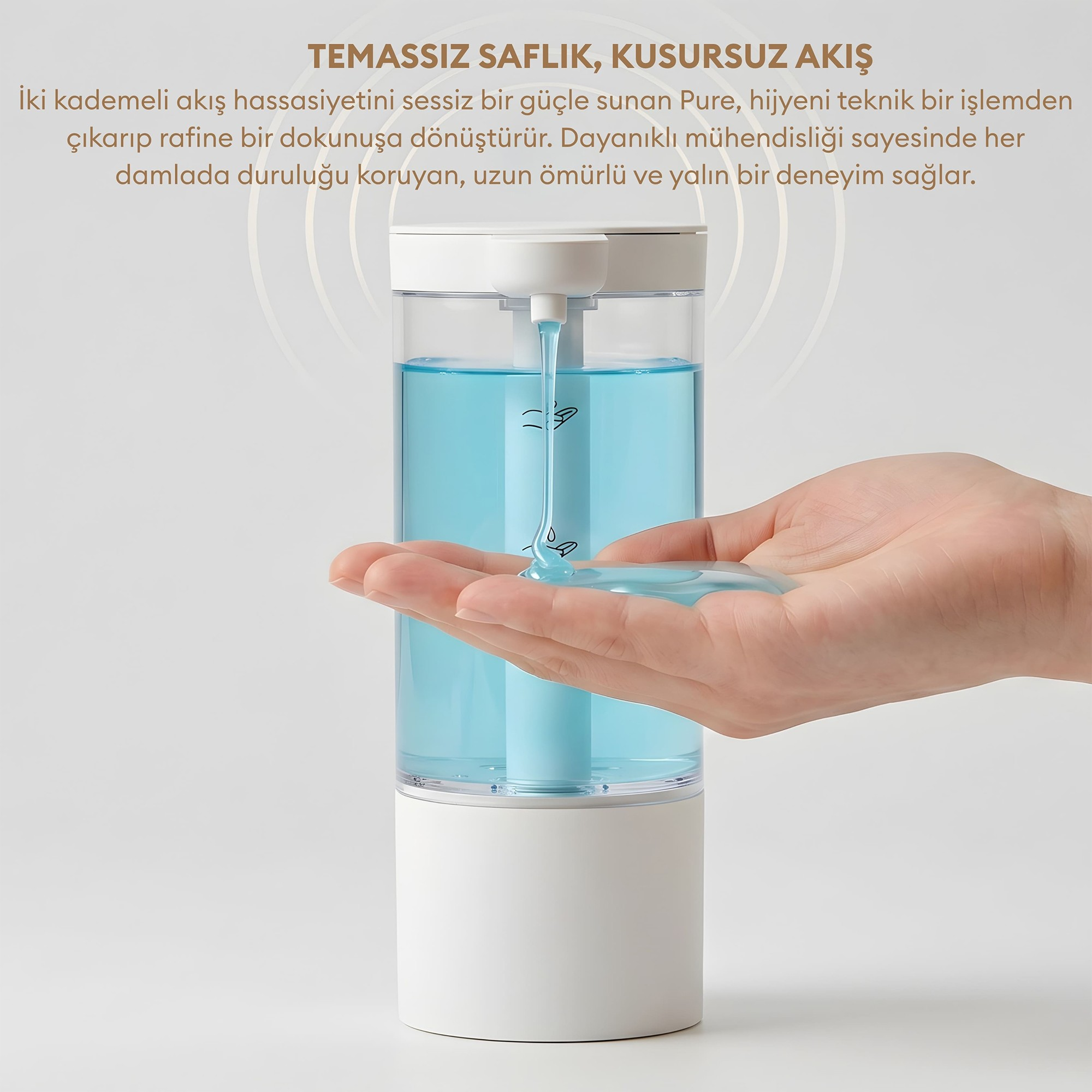 Otomatik beyaz sabunluk, açık bir ele mavi sabun akıtıyor. Üstte Türkçe metin var.