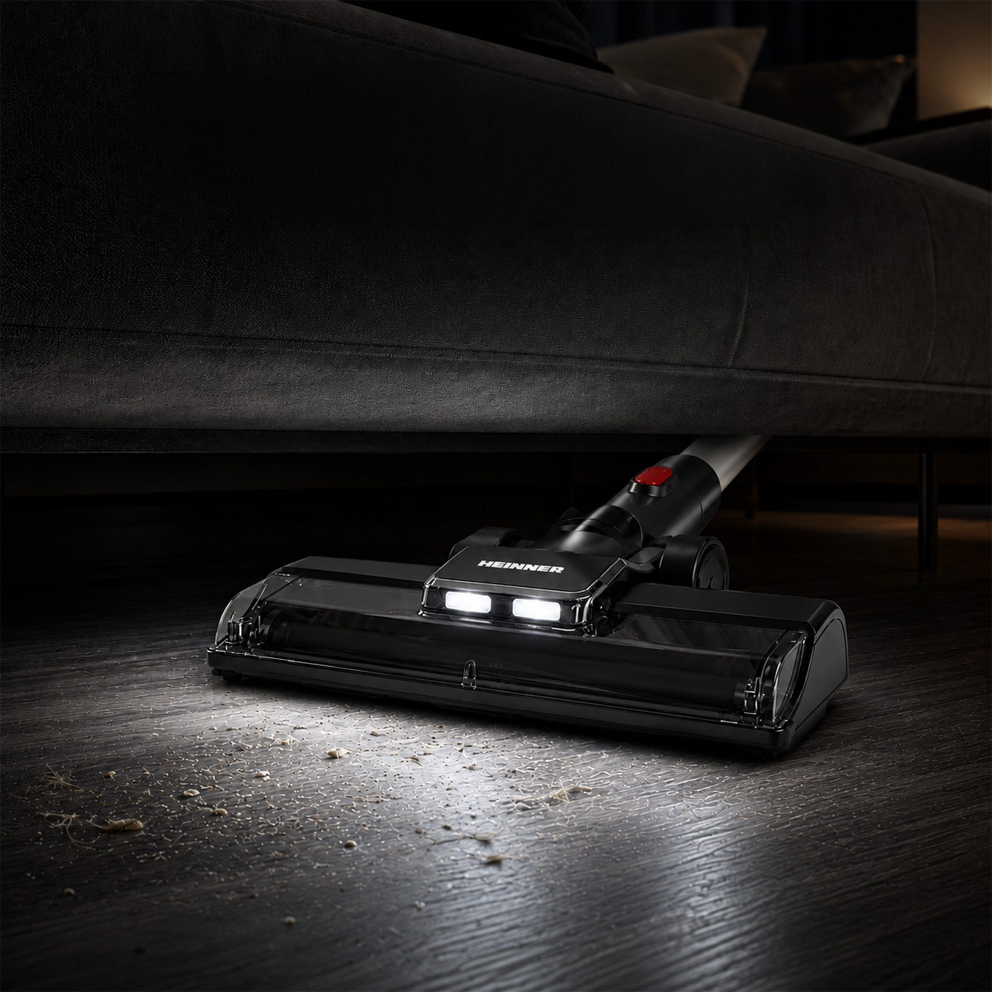 Een zwarte stofzuiger met LED-lampjes reinigt de donkere houten vloer onder een bank.