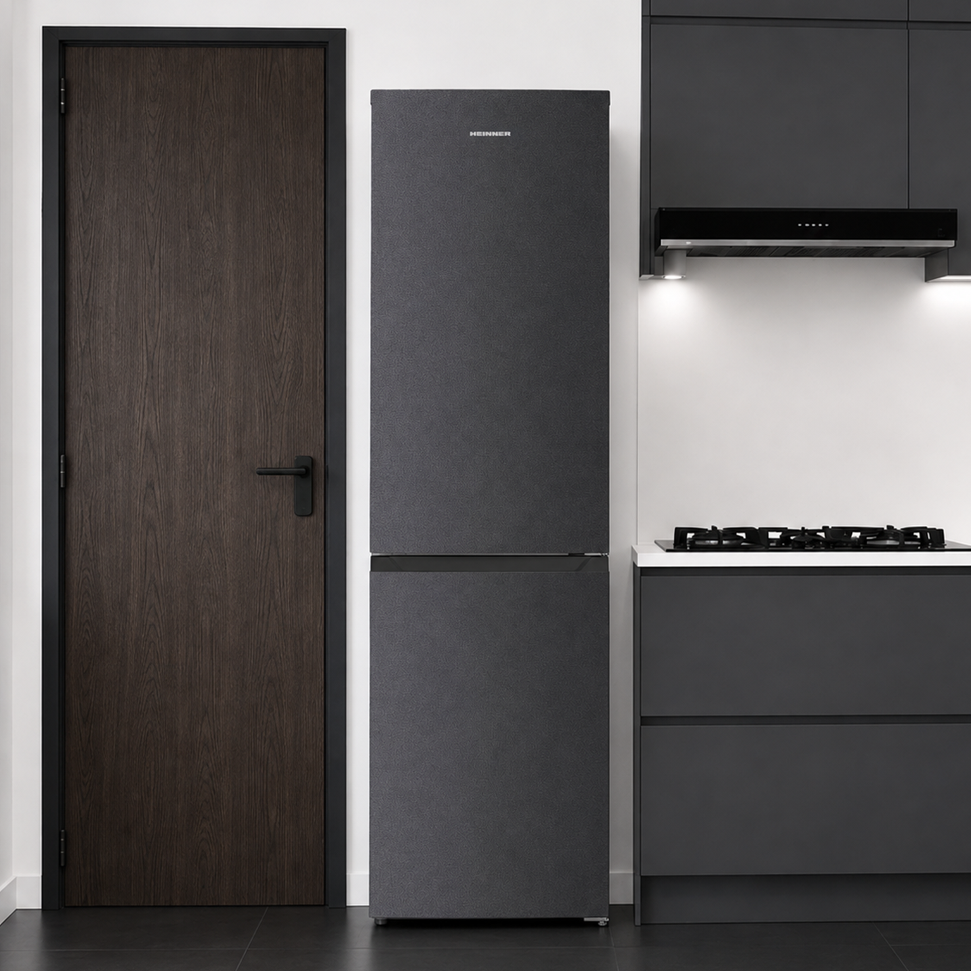 Cuisine moderne grise avec réfrigérateur sombre, porte en bois et table de cuisson.