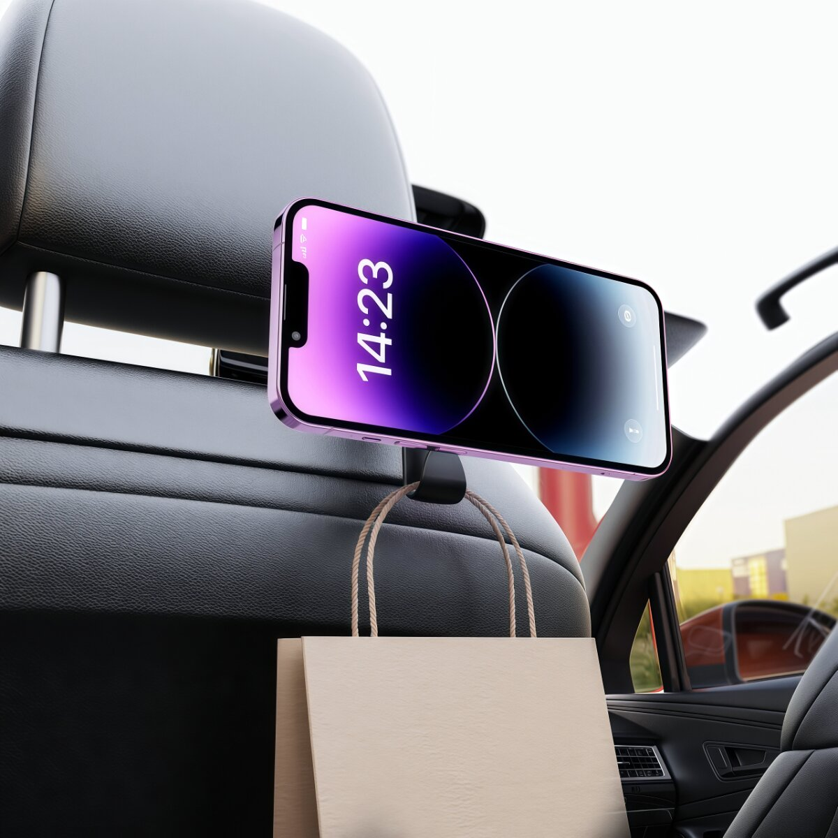 Ein Smartphone an einem Autositzhaken hält eine Papiertüte.
