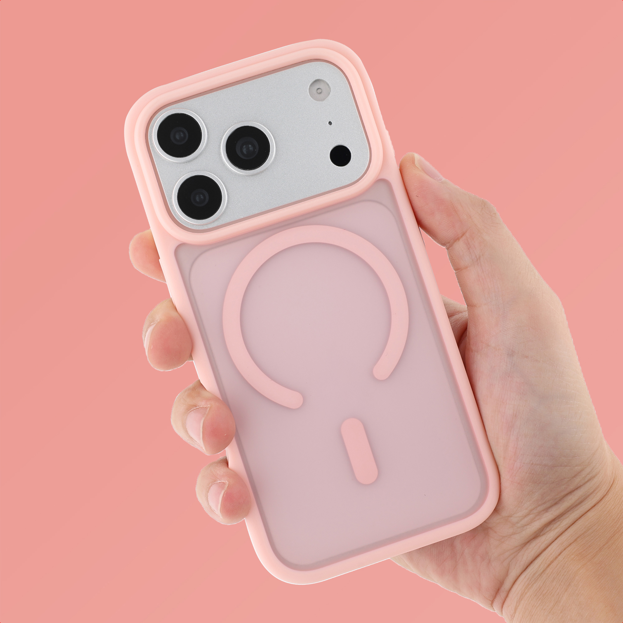 Eine Hand hält eine rosa Handyhülle mit Magsafe-Ring und Kameraaussparung vor einem rosa Hintergrund.