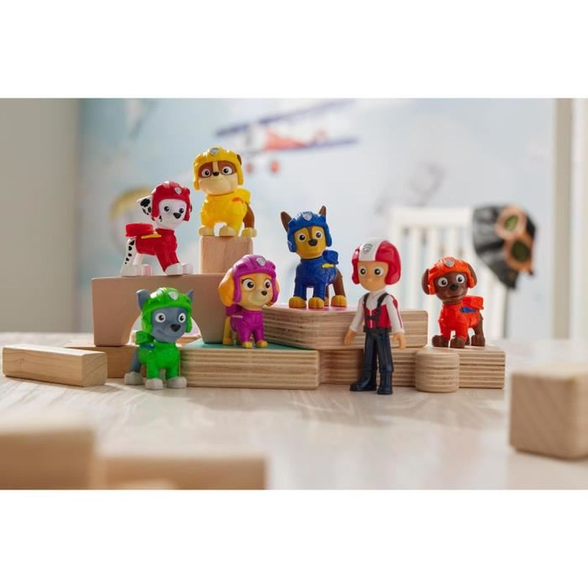 Paw-Patrol-Figuren stehen auf Holzblöcken vor einem verschwommenen Hintergrund.