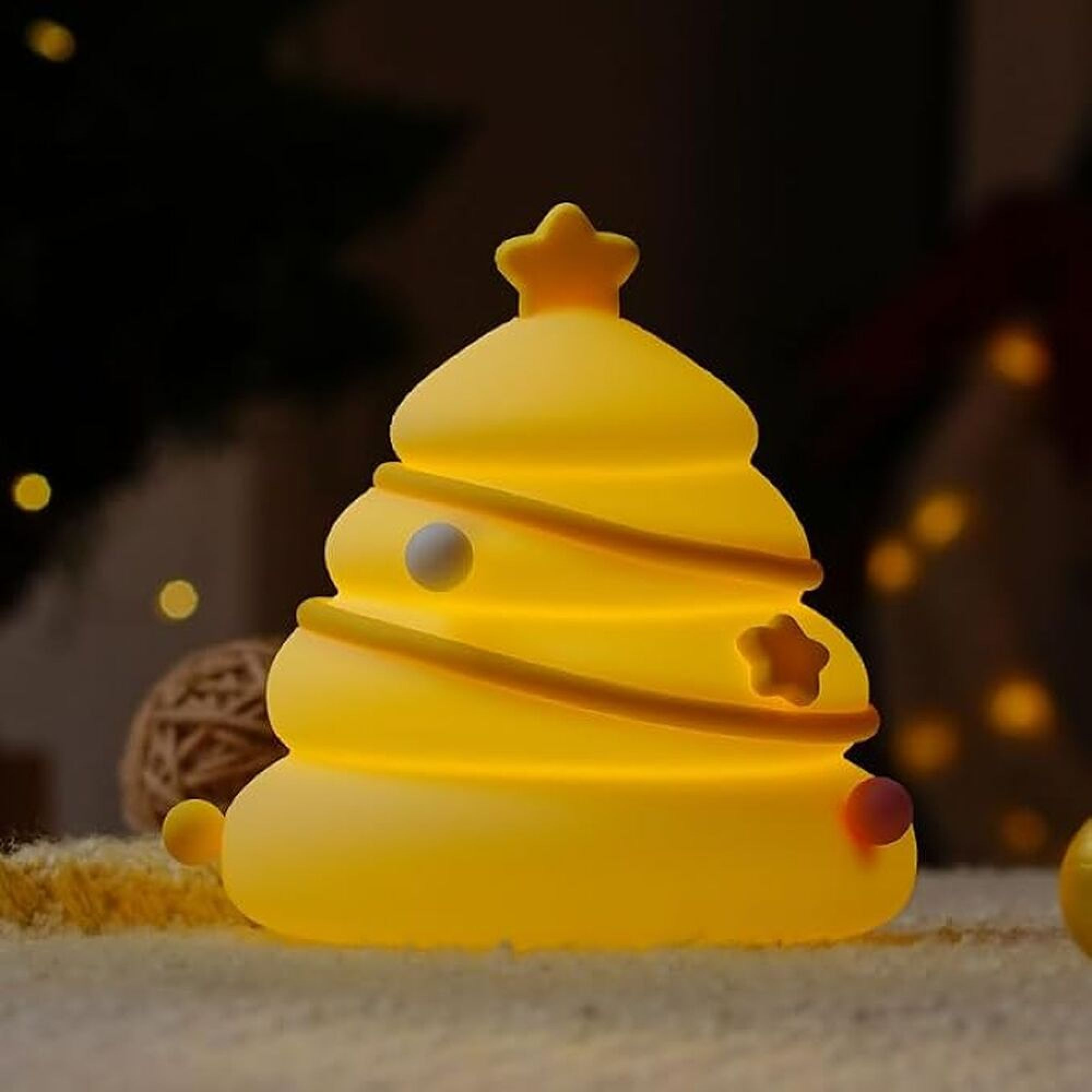 Ein leuchtendes gelbes Silikon-Nachtlicht in Form eines Weihnachtsbaums mit Stern auf dunklem Hintergrund.