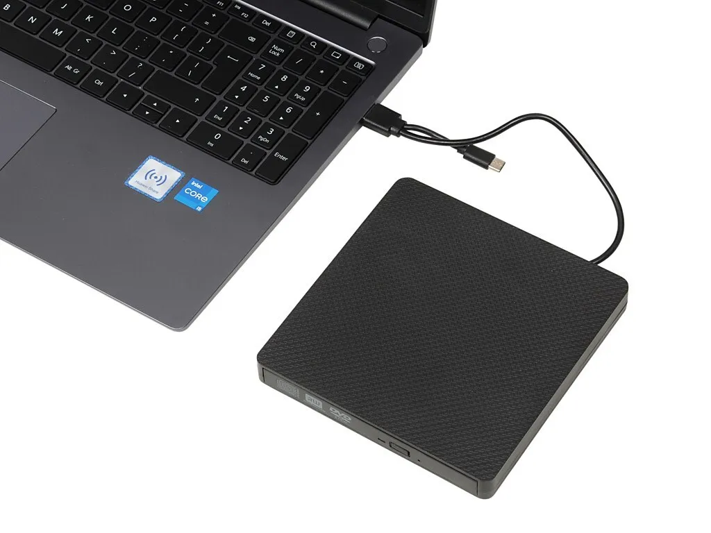Ein schwarzes externes DVD-Laufwerk ist per USB-Kabel an einen grauen Laptop angeschlossen.