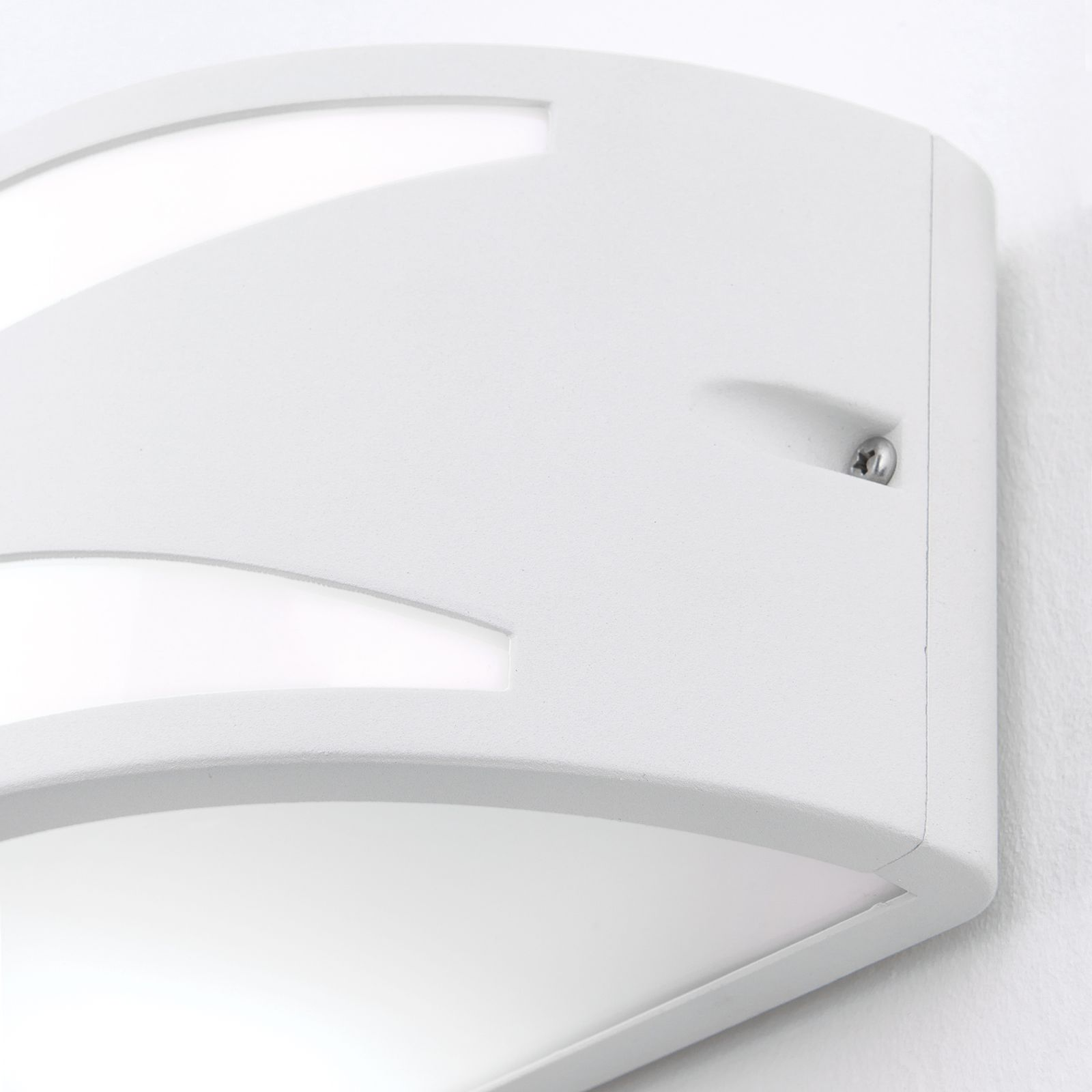 Eine moderne weiße Wandleuchte mit geschwungenen Ausschnitten an einer weißen Wand.