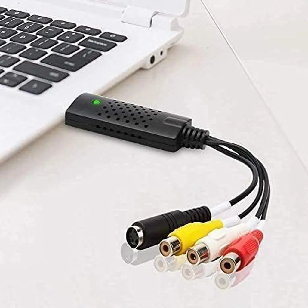 Ein USB-Audio-Video-Adapter mit RCA-Anschlüssen liegt neben einem Laptop auf einem Tisch.