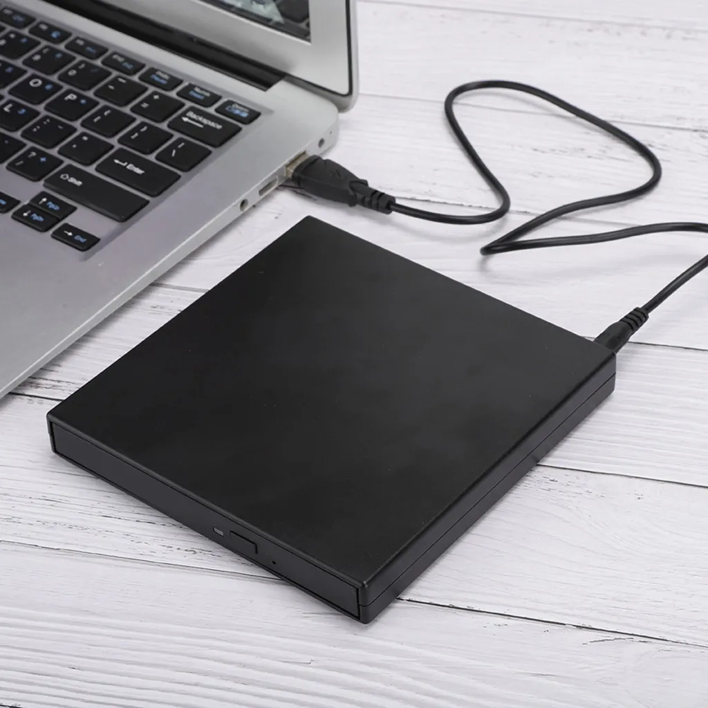 Ein schwarzes externes Laufwerk ist per Kabel an einen Laptop auf einer weißen Holzoberfläche angeschlossen.
