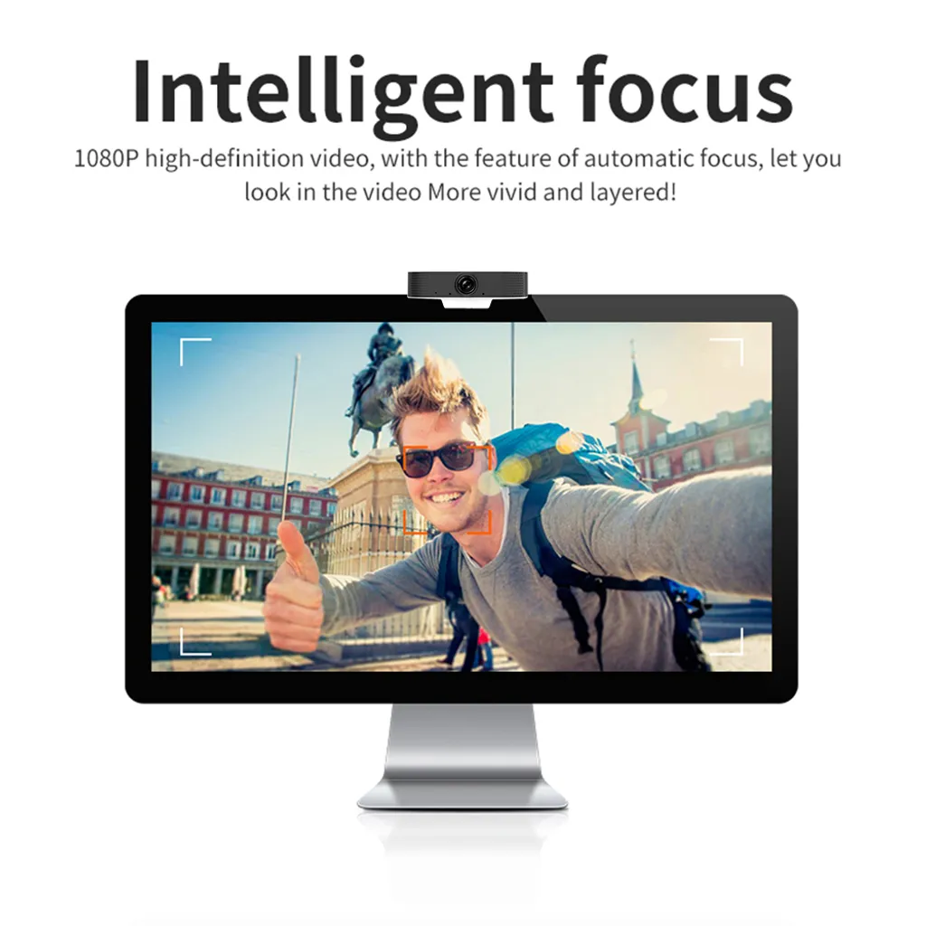 Ein Computermonitor mit Webcam zeigt einen Mann, der vor einem Gebäude selfieartig in die Kamera lächelt.