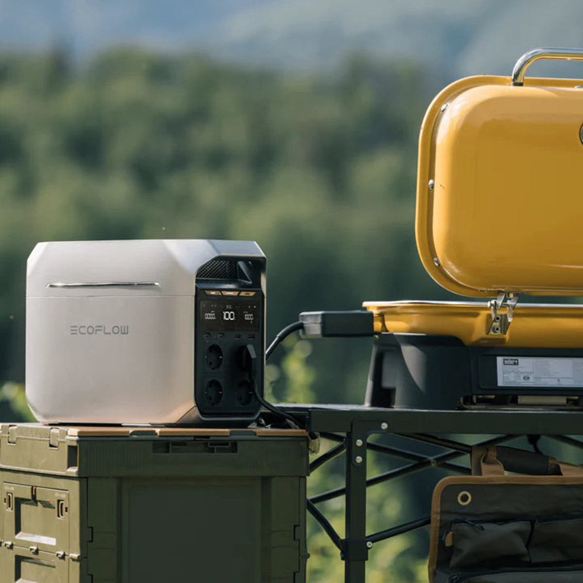 Una estación de energía EcoFlow en una caja verde, conectada a una parrilla amarilla al aire libre.
