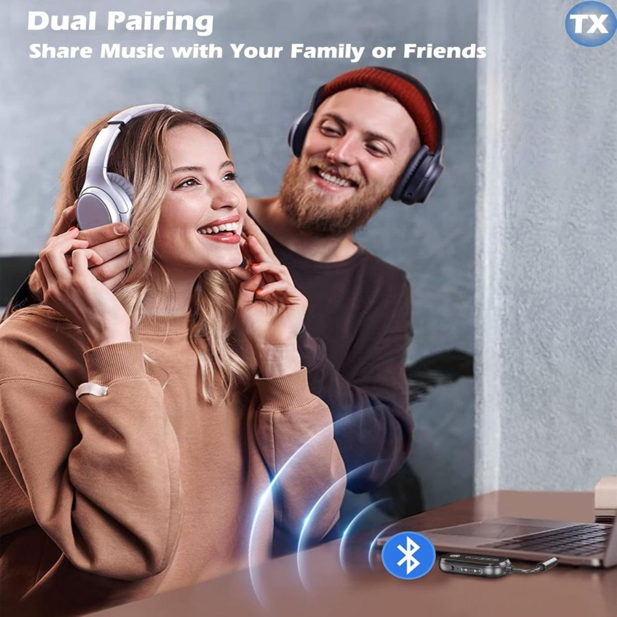 Ein lächelndes Paar mit Kopfhörern und einem Bluetooth-Sender auf dem Tisch.