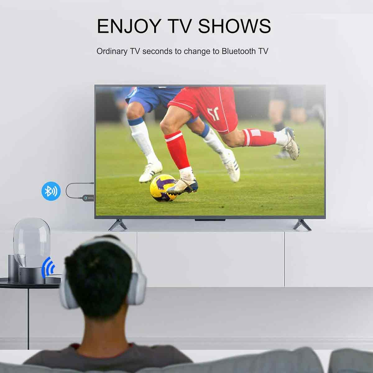 Eine Person mit Kopfhörern sieht ein Fußballspiel auf einem Fernseher, verbunden über einen Bluetooth-Adapter.