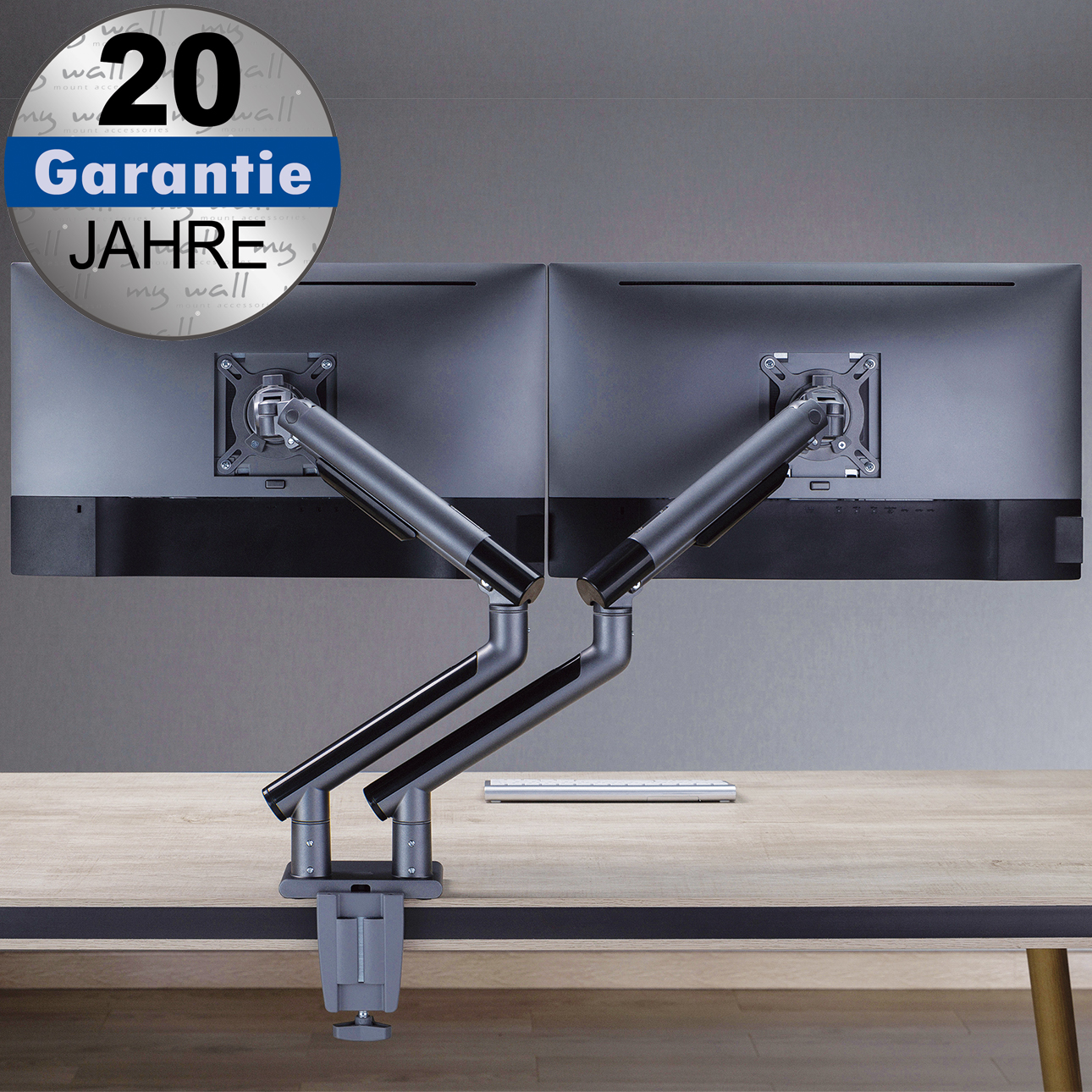Zwei Monitore an einem silbernen Doppelarm-Tischhalter, befestigt an einem Holztisch mit einer Schraubklemme.
