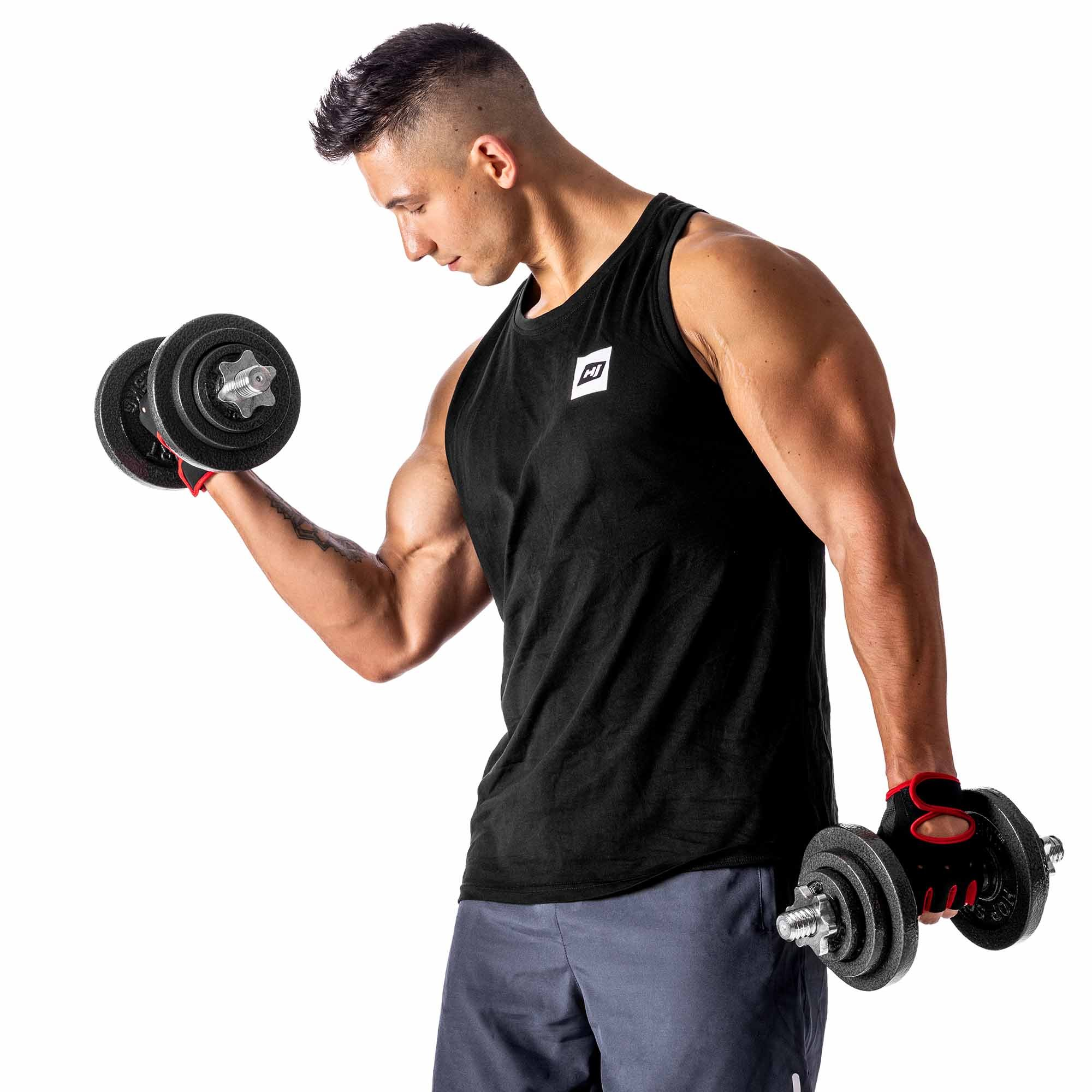 Ein muskulöser Mann in schwarzem Tanktop und grauen Shorts hebt Hanteln vor weißem Hintergrund.