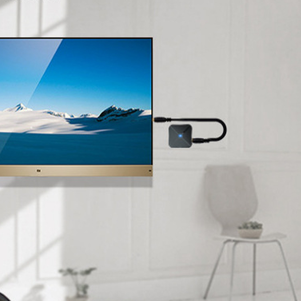 Ein Fernseher mit Berglandschafts-Bild, ein kleiner schwarzer Adapter seitlich angeschlossen, im Raum ein Stuhl.